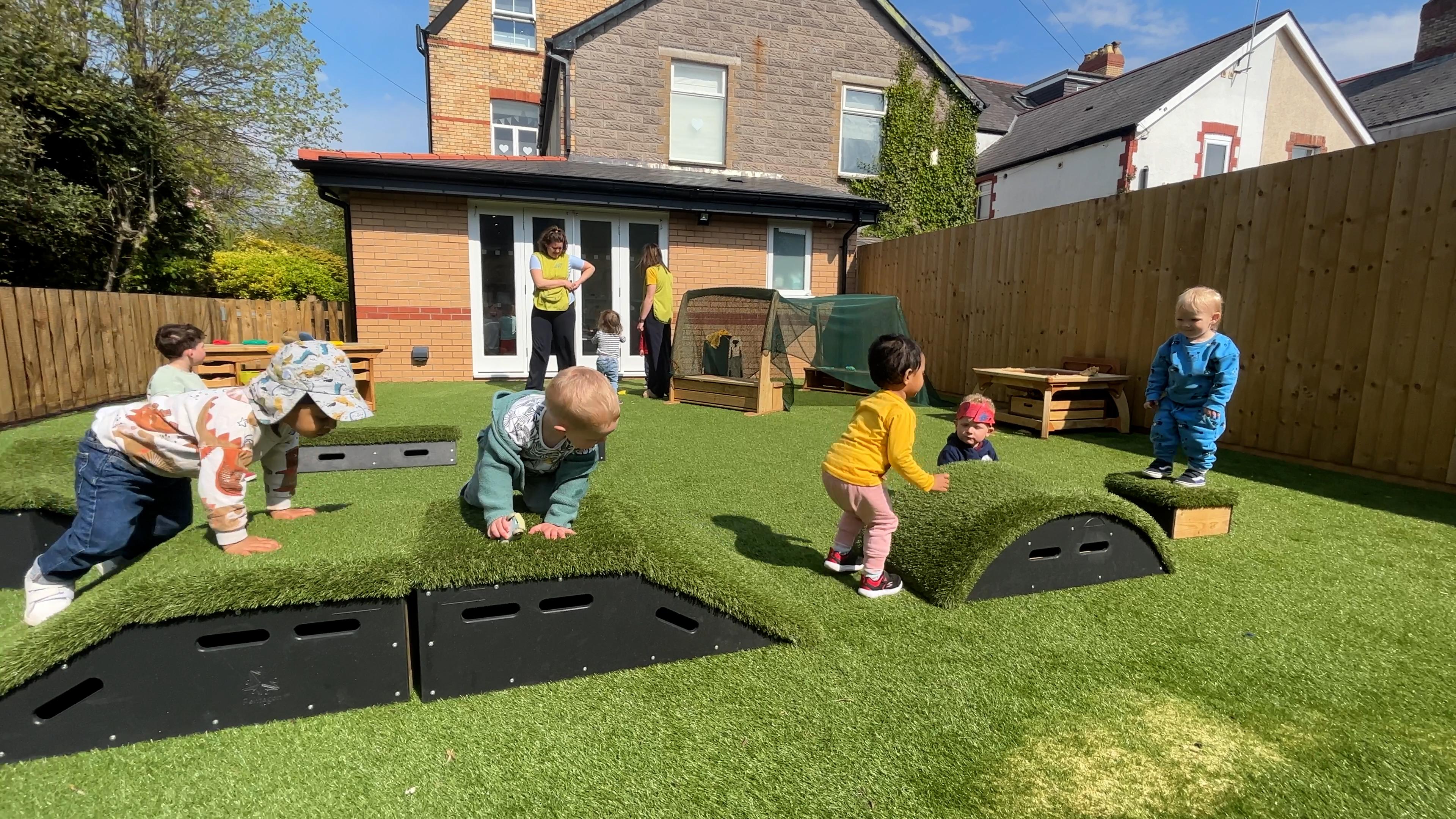 Young children stepping through a trail of grass topped blocks