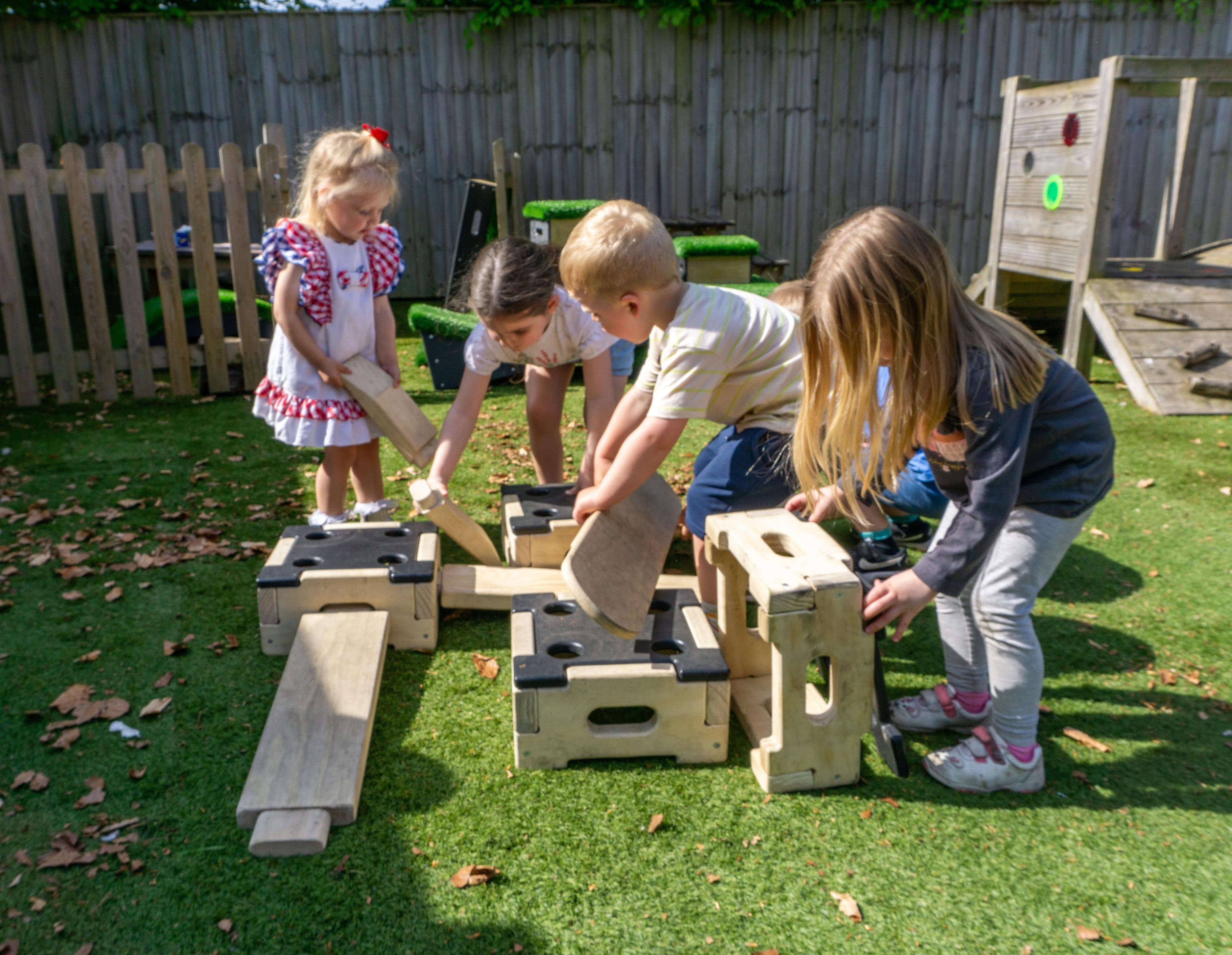 A group of children working together to move block and planks to create a trail