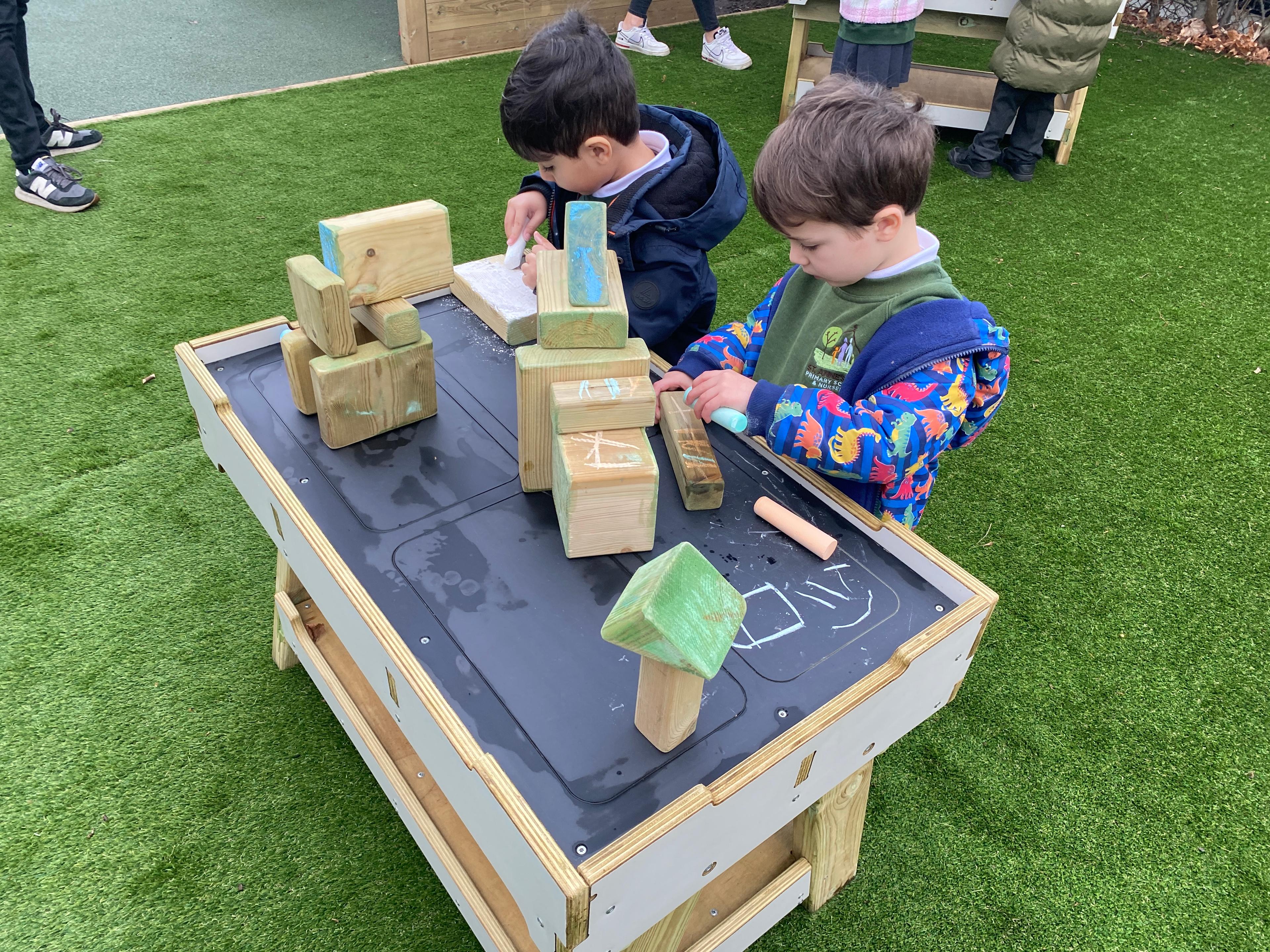 Two young boys playing with blocks on a construction bench
