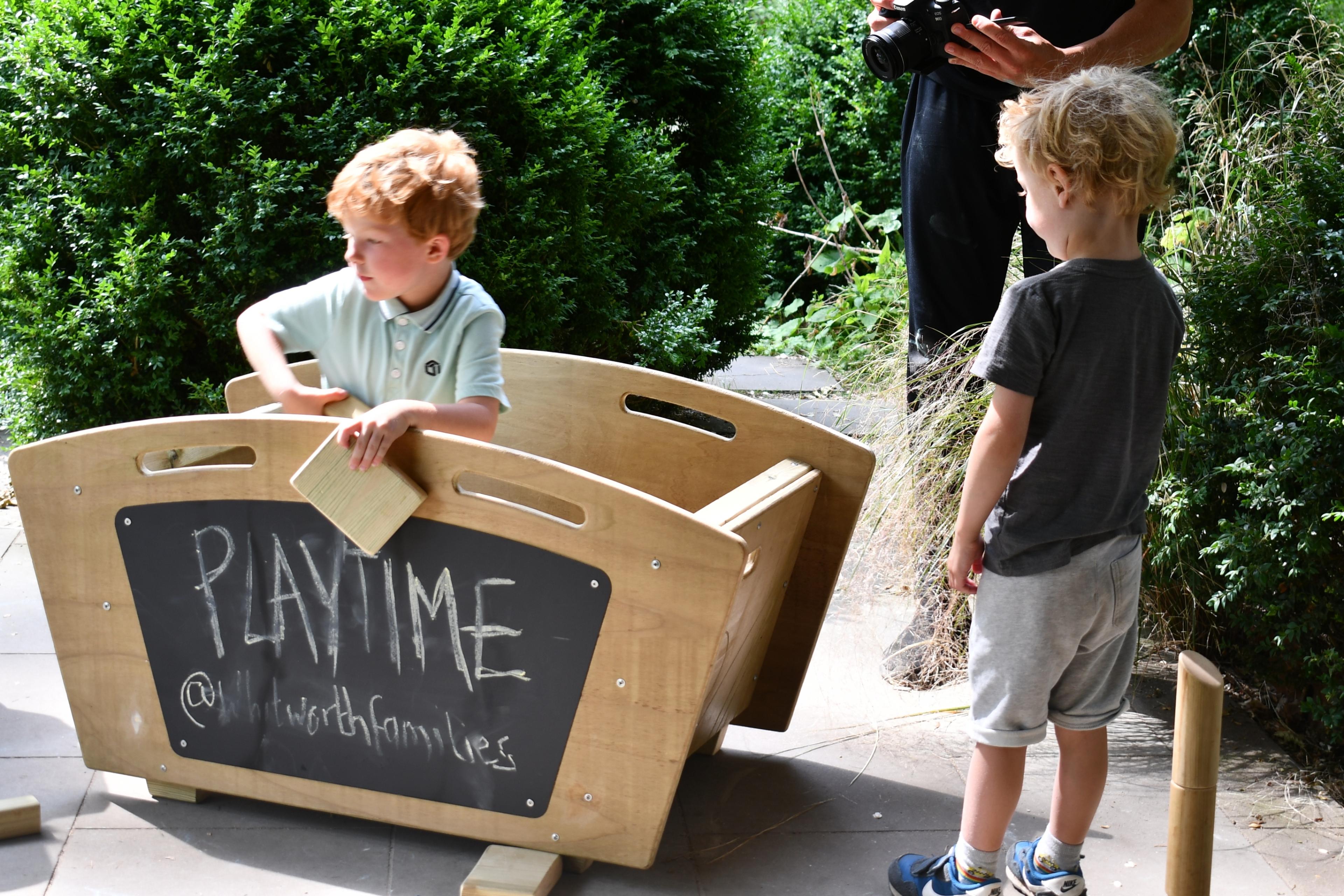 Two boys playing in a wooden skip