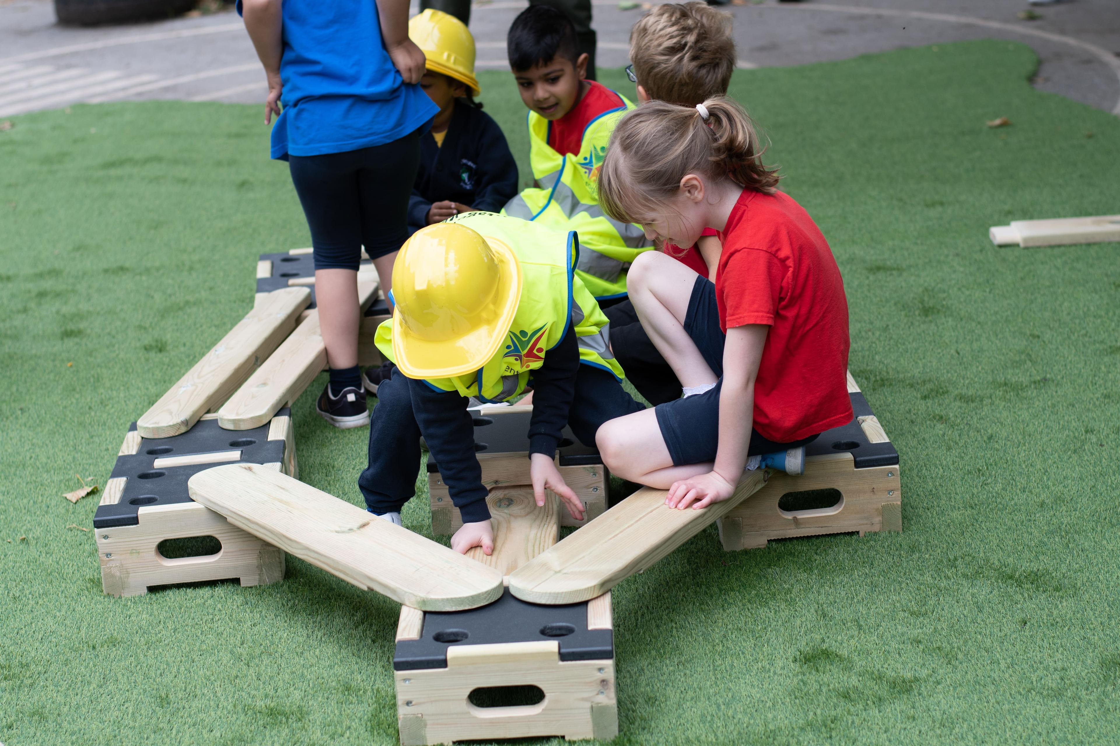 A group of children constructing a trail using the play builder blocks and planks.