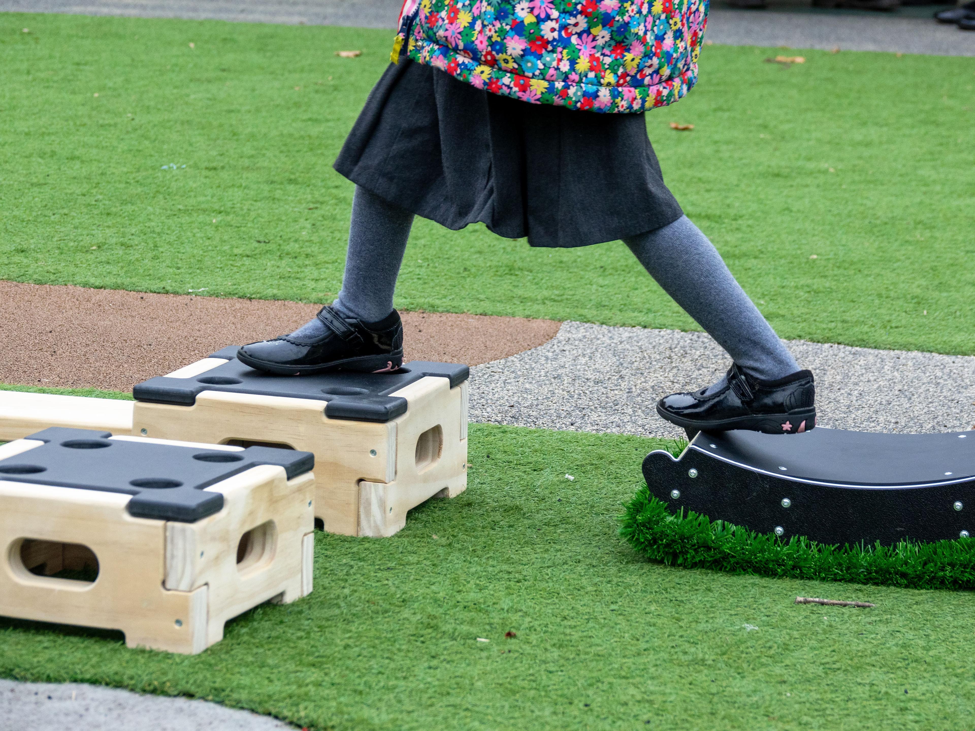A child stepping from one of The Rockie balance blocks on to a play builder block