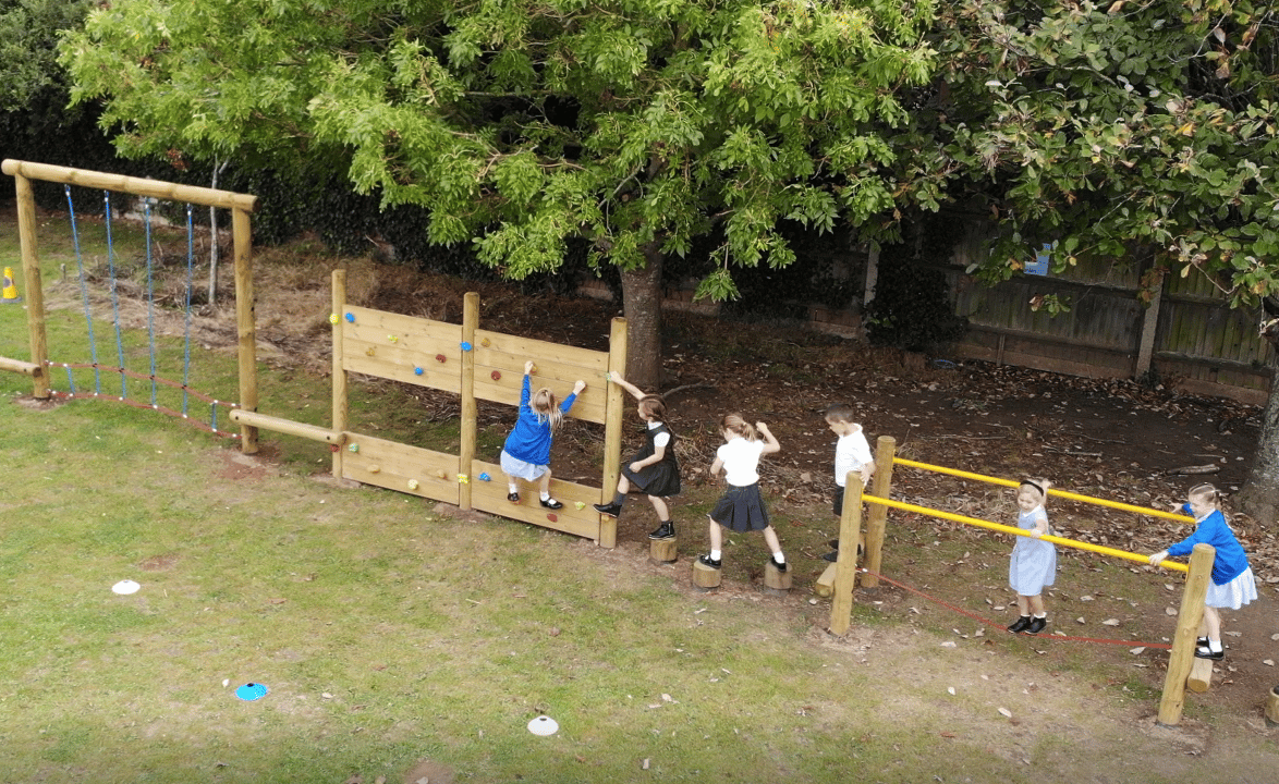 an infant trim trail with a climbing wall and stepping logs