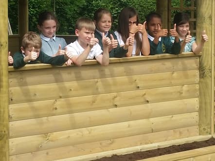 School children sitting in a wooden gazebo.
