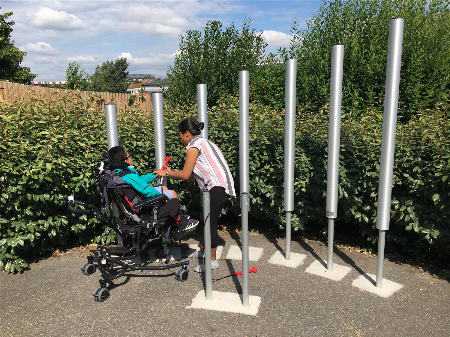 a child on a wheelchair playing music using in-ground chimes