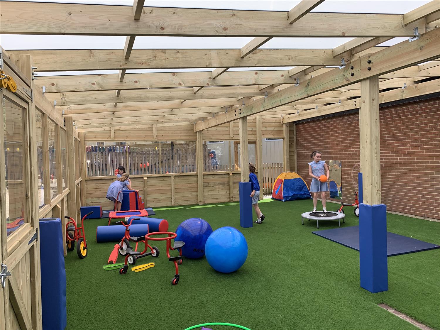 Children playing on artificial grass underneath a timber canopy