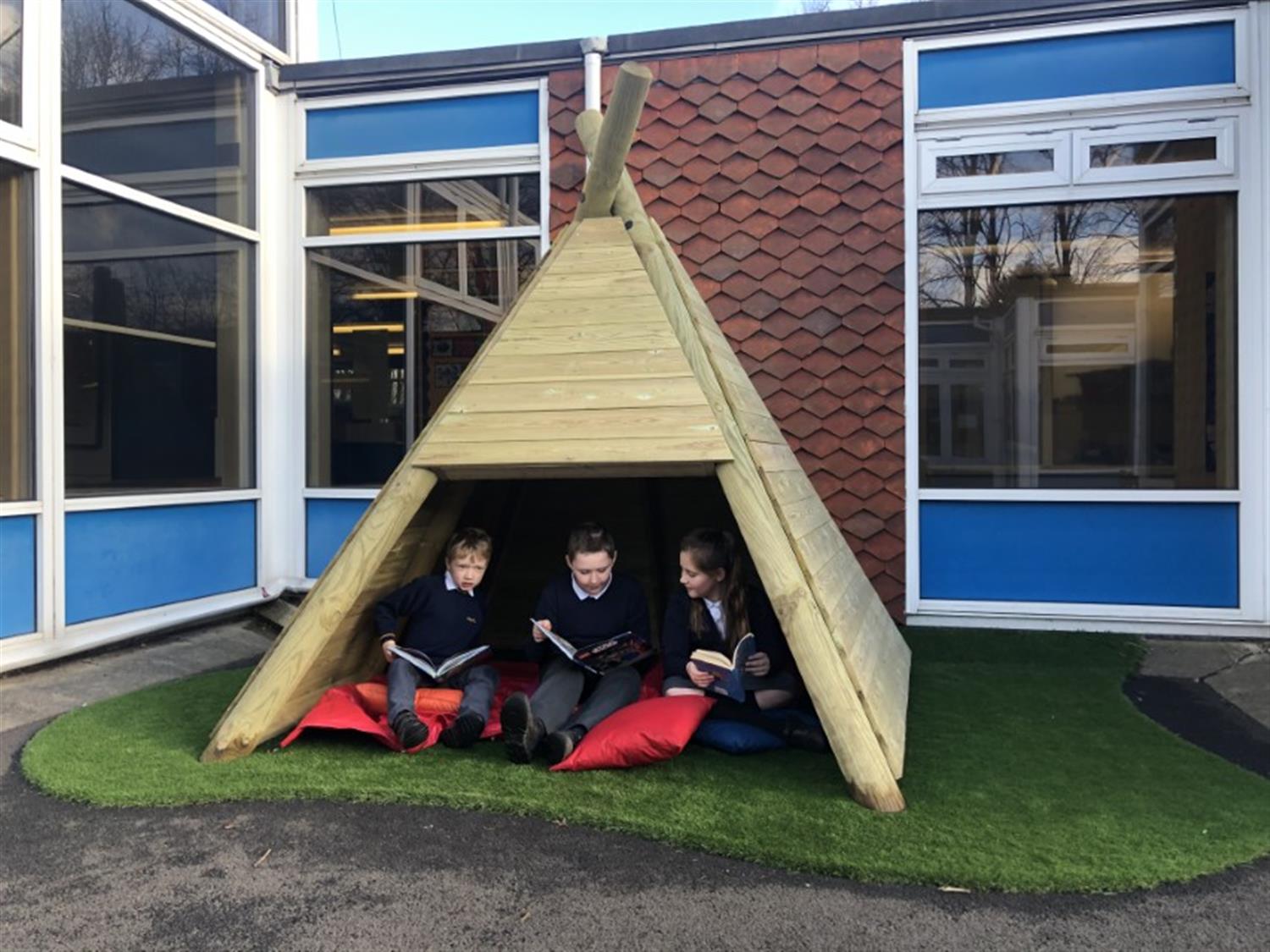 children reading in a playground den 