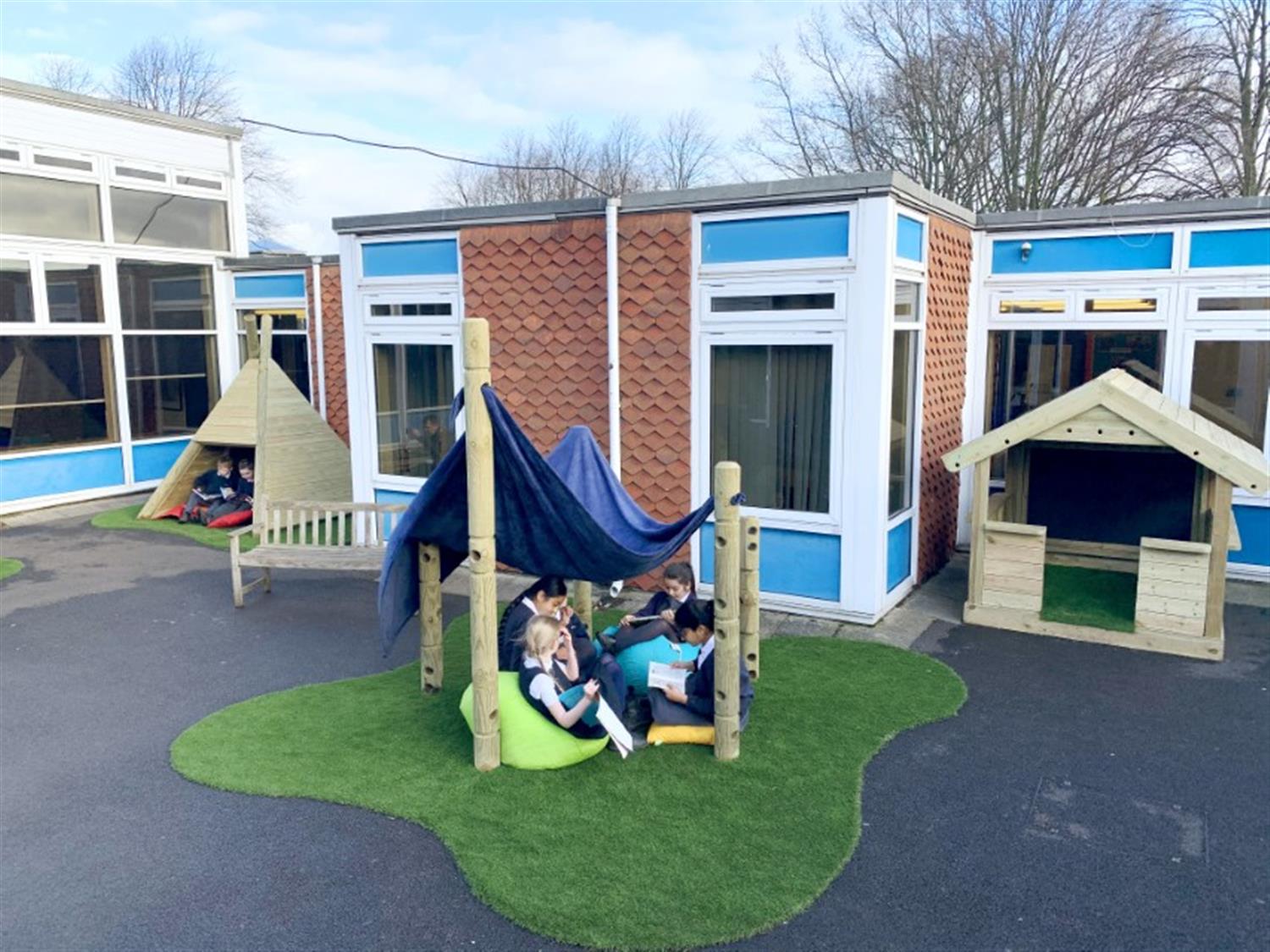 children sitting in a playground den created by den making posts