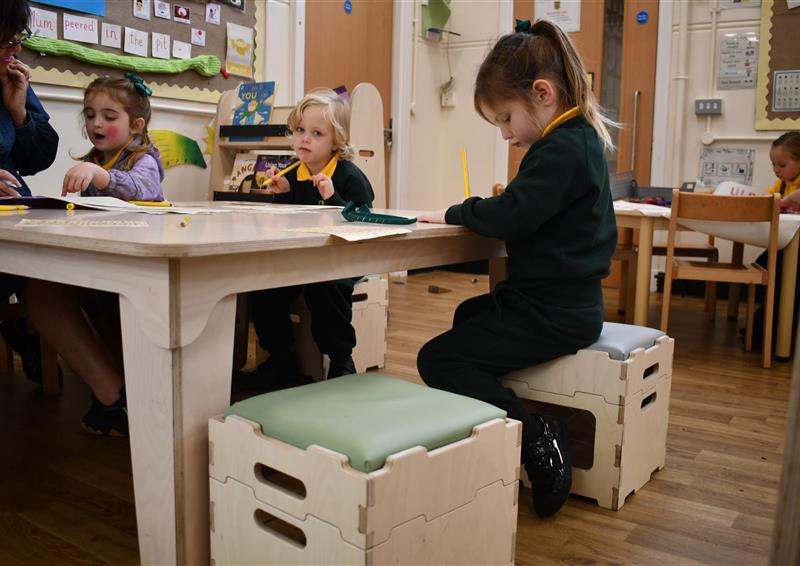 Two pupils in a classroom sat next to each other on Stack and Sit stools