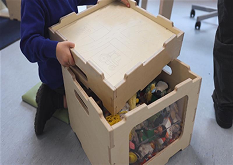Close up of school pupil lifting the lid off the Stack and Sit stool to access the storage space within it 