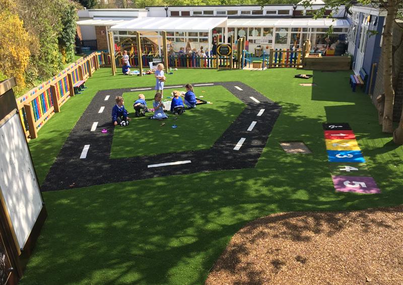 artificial grass surface that has been installed at a eyfs setting. The surface has Saferturf markings installed on it, with a road and a number line being shown.
