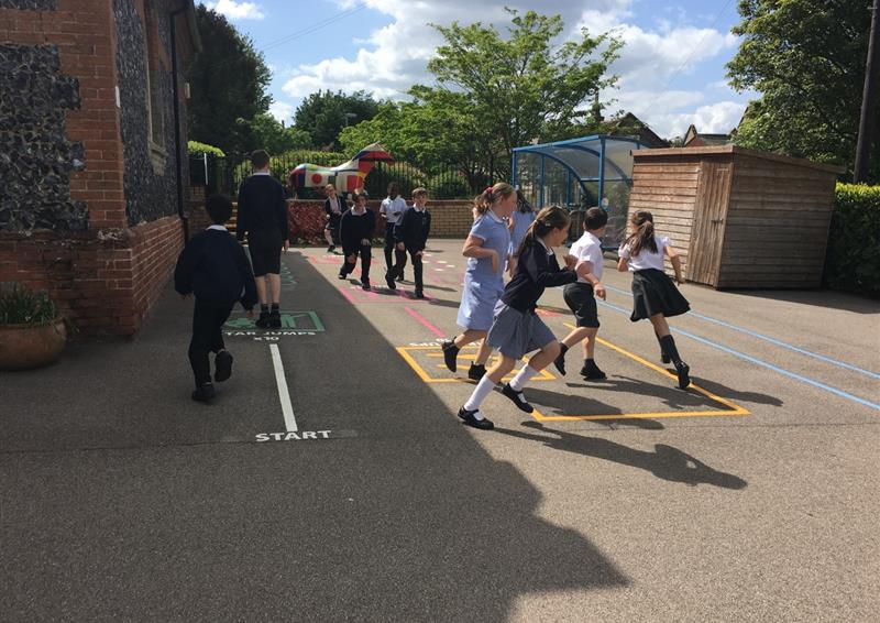 A large group of children are playing with our thermoplastic line markings. A variety of different colours are being used to create the playground. The surface of the play area is tarmac.