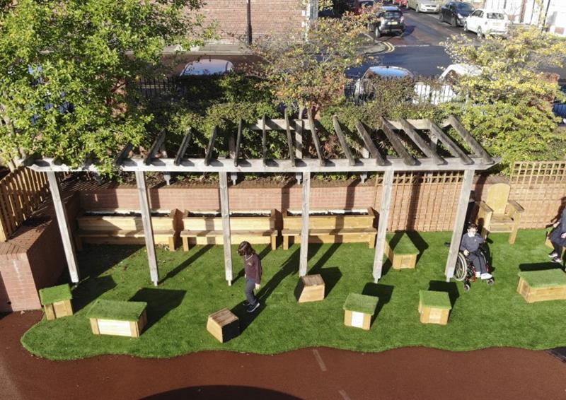 Green artificial grass that has been installed underneath a wooden canopy. Get Set, Go! Blocks have been placed underneath the canopy too, with some children playing with them.