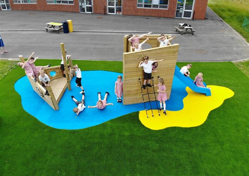 16 children playing on our playship, 2 children are lying on the blue wet pour acting as if they are in the water around the ship.