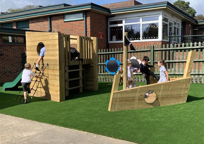 7 children playing on our playship, 1 boy is climbing up the ropes and the rest of the children are playing on or around the ship.