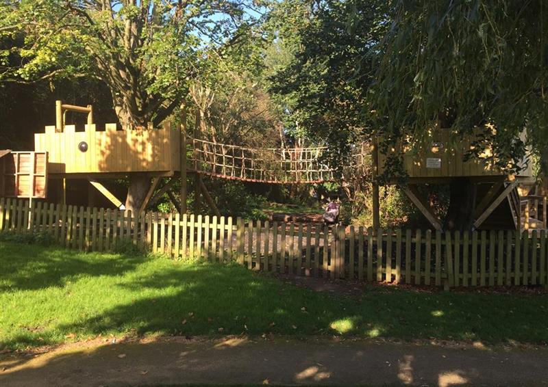 A side view of the bespoke treehouse, there are two platforms with a bridge with netting running between them.