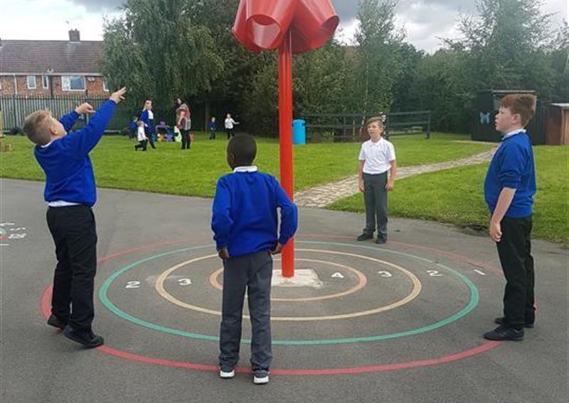 5 children playing in the playground throwing balls in to the 4 way ball shoot. 