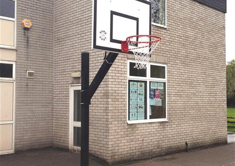 A side view of a adjustable basket ball post, there are no children playing around this piece of equipment.