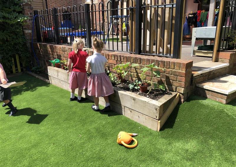 2 children planting plants into the straight planter.
