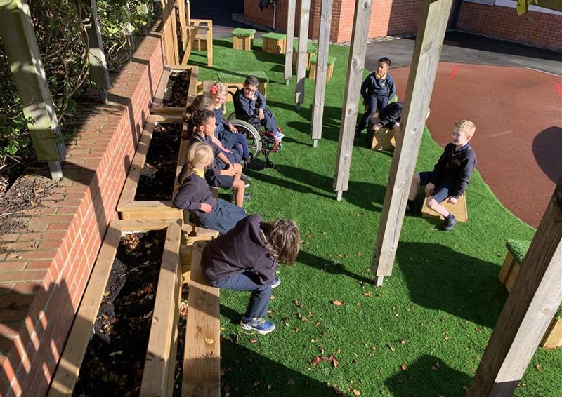 A class of children sat on the planter benches that are underneath the canopy