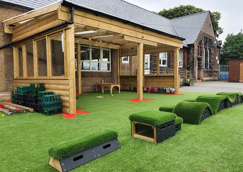 a timber canopy with green artificial grass and saferturf splashes in red around the  bottom of the poles with our get so, go! blocks in front