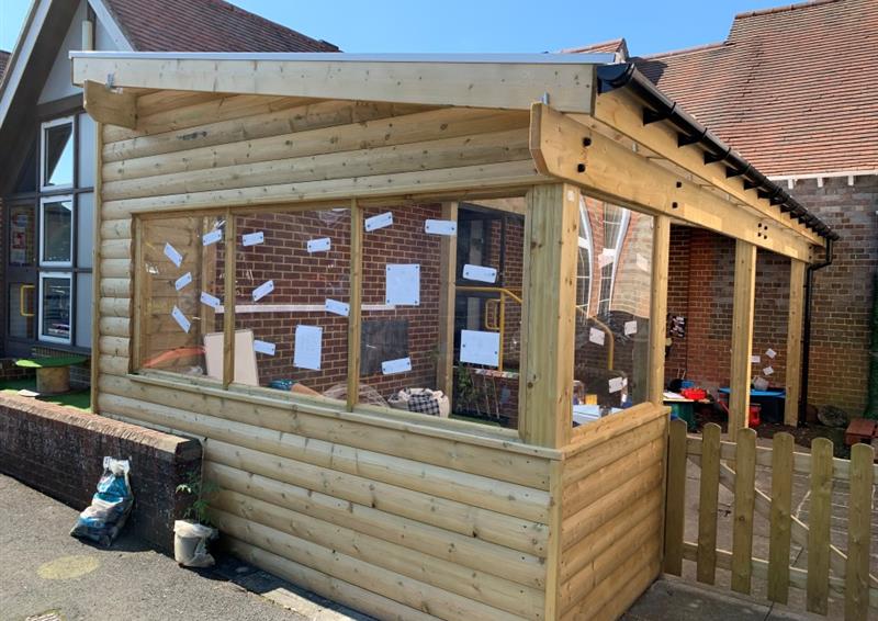 The side of a timber canopy with a window that is being used to display classroom resources