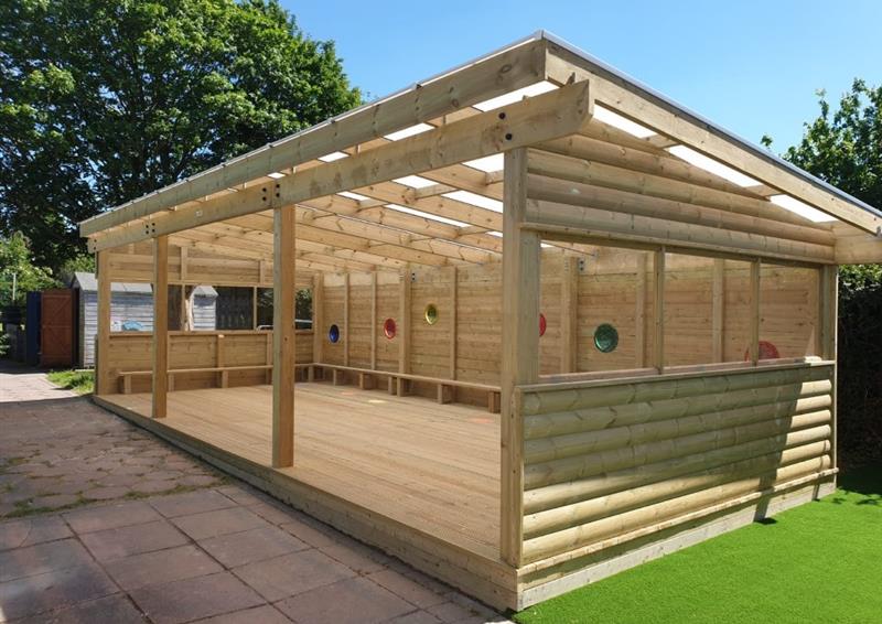 a timber canopy with a declining roof and open sides with circular windows on one side