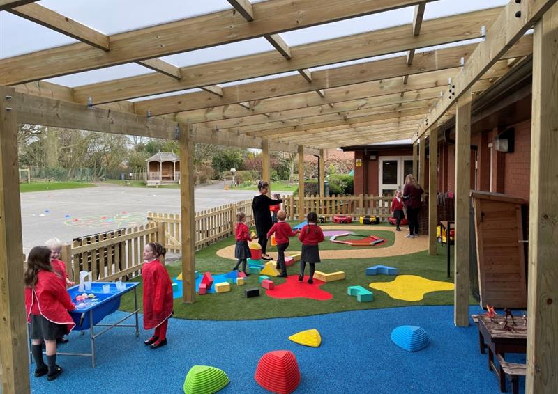 a timber canopy with blue and green safety surfacing beneath with yellow and red saferturf splashes