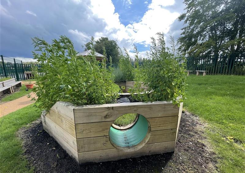 A side view of the immersive planter, a pentagon shaped planter with a climb through tunnel in the middle.