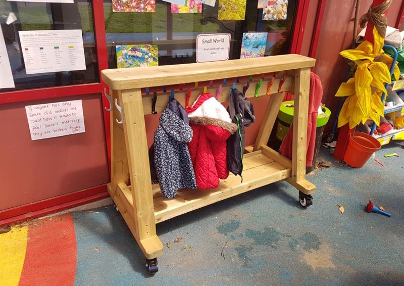 a timber coat rack on wheels with rainbow hooks and little coats hung on them outside a nursery