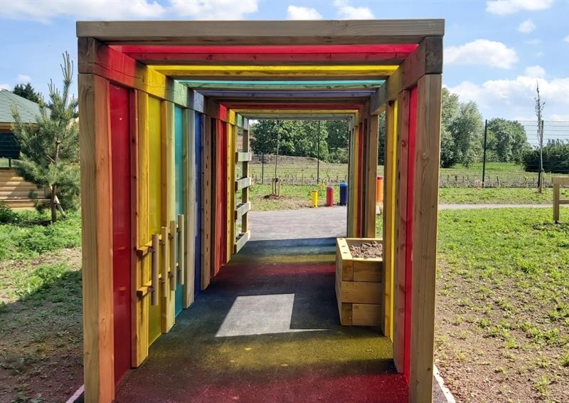 a look through the sensory tunnel showing the sunlight streaming through the coloured panels causing a rainbow effect on the surface below