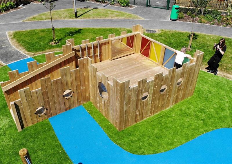 A birds eye view of children playing on the play tower, there are coloured sensory panels around the tower, with a ramp leading up to it.