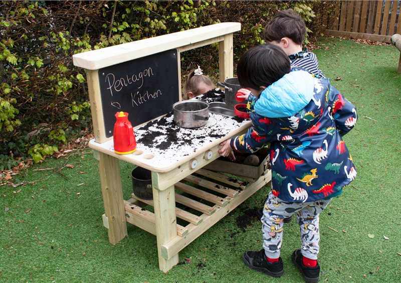 A young boy playing on the low cost mud kitchen in his playground 
