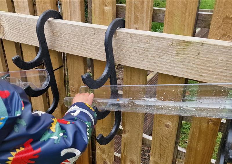 A young boy moving the water channels that are hooked onto the fence in their playground