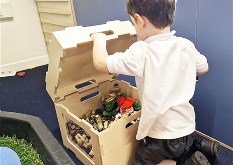 A school child opening lid of storage in Stack and Sit Stool.