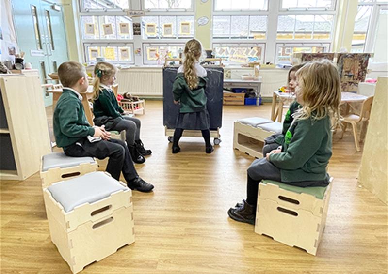 School children using Art Easel and sitting on Stack and Sit Stools.