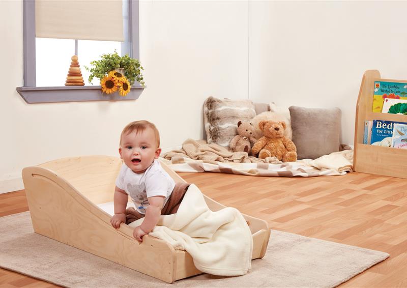 A baby is sat in the Sleep Pod which is in a classroom. 