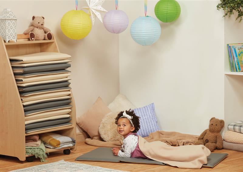 A little girl is lying on a sleep mat next to the Mobile Sleep Mat Store.