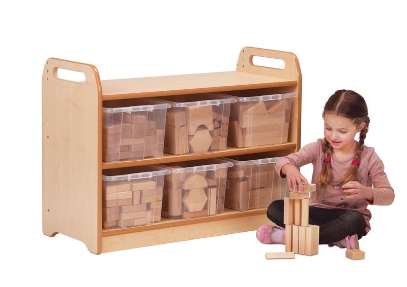 A young girl is building a tower from wooden blocks sat in front of the Block Play Unit with blocks neatly organised inside the six plastic tubs.  