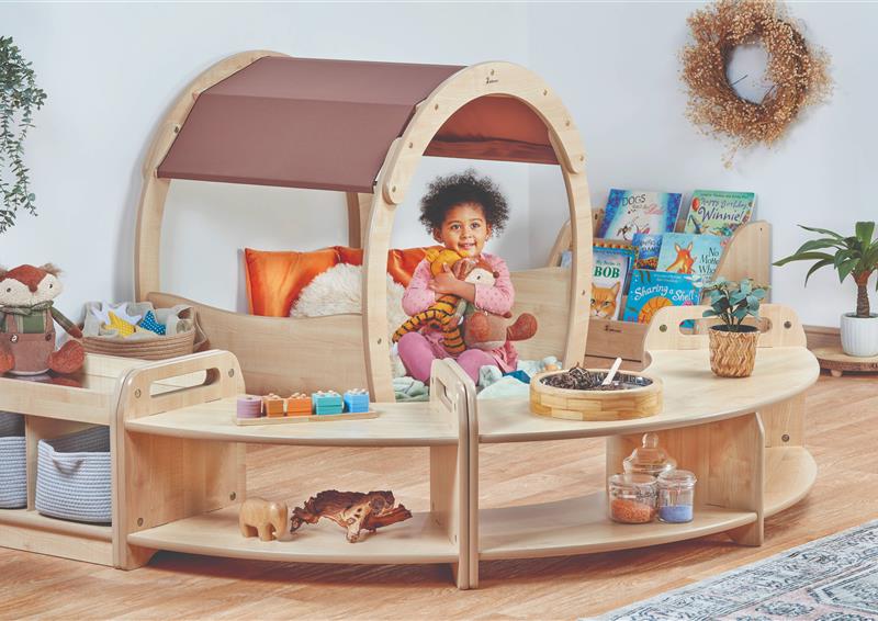 A young girl is sat playing in the Curious & Cosy Zone, in a classroom