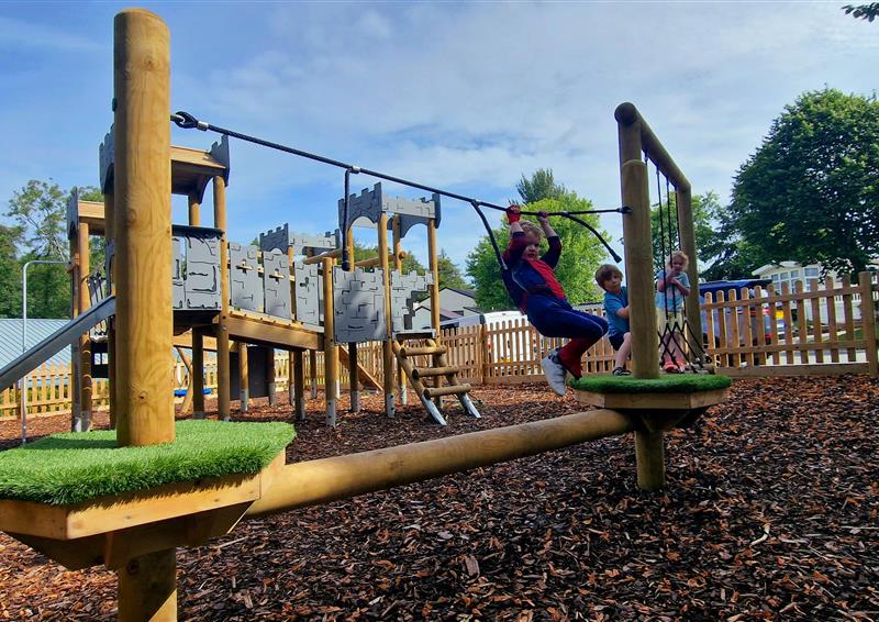 child climbing on trim trail in holiday park play area